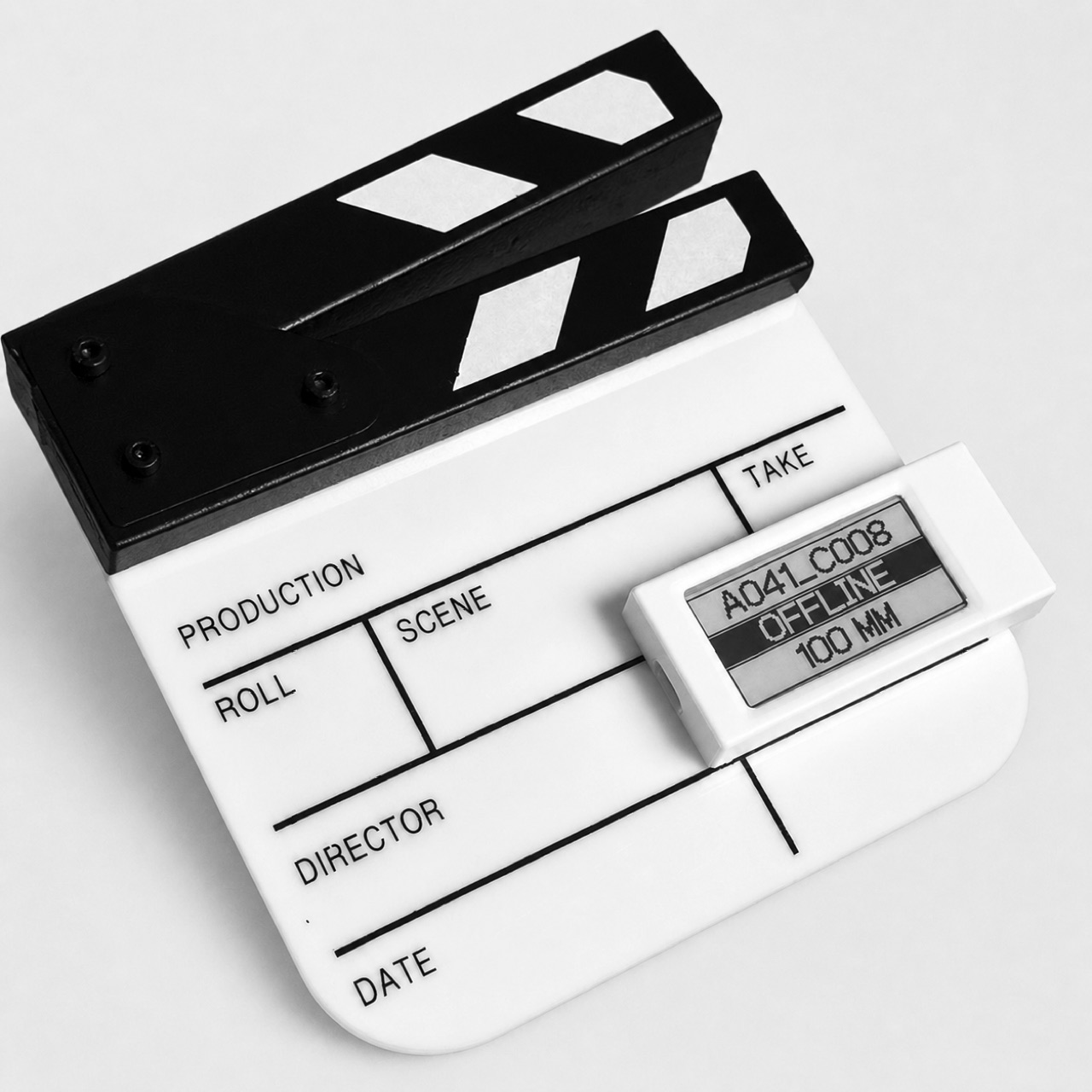 Cineink e-ink display in its 3D-printed enclosure, clipped to a clapperboard, showing A041_C008 / OFFLINE / 100 MM